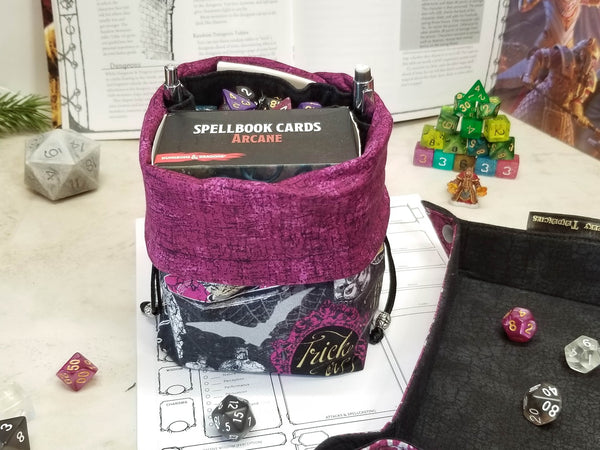 Halloween potions dice bag. Halloween print in black, metallic silver and purple with pops of gold. Bag folded down to show purple lining
