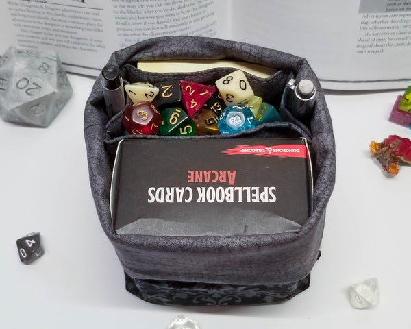 Black and grey damask print dice bag. Open to show grey lining and pockets.