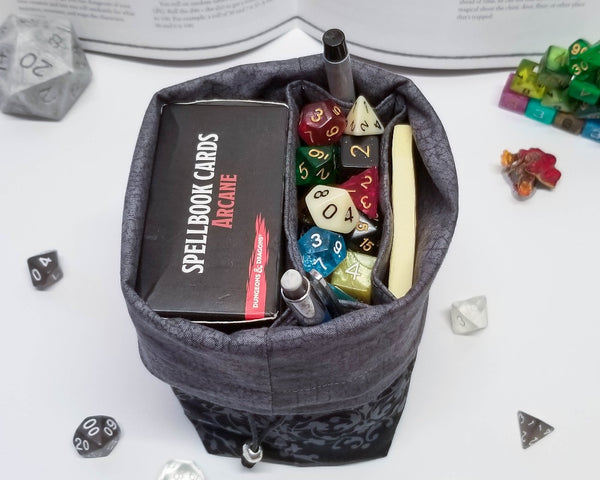 Black and grey damask print dice bag. Open to show grey lining and pockets.