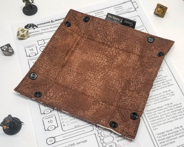 Dungeon map print dice tray, lined with brown crackle fabric, unsnapped and flat.