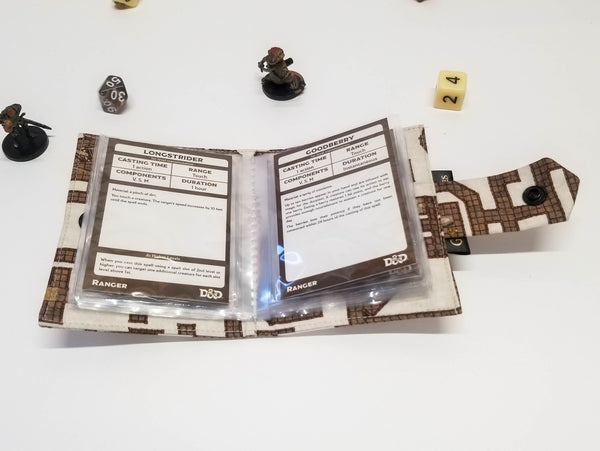 Spellbook made from fabric with a dungeon map on a light background. Open to show card sleeves