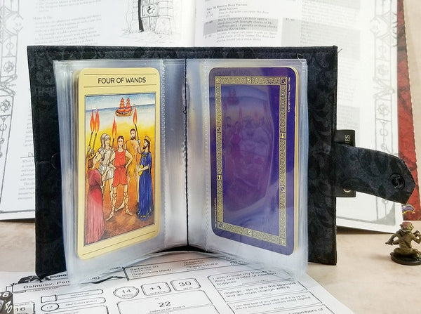Tarot-sized spellbook in black damask open in front of an adventure module.
