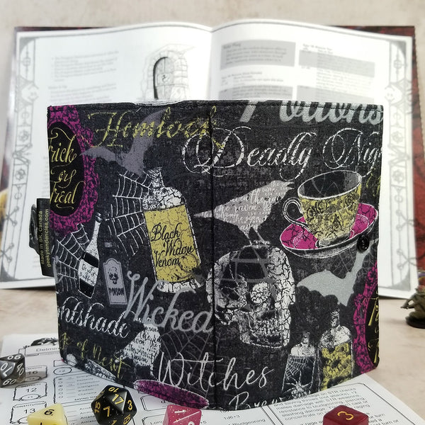 tarot-sized spellbook in a metallic silver halloween print. Back view showing spine and overall print featuring potions, ravens and skulls