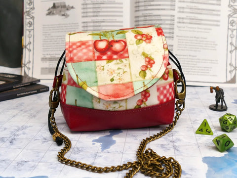 Patchwork-style handbag with floral pattern on a table with gaming dice and board