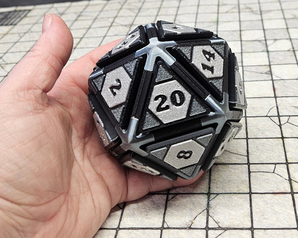A silver d20 fidget clicker is held in a hand for scale