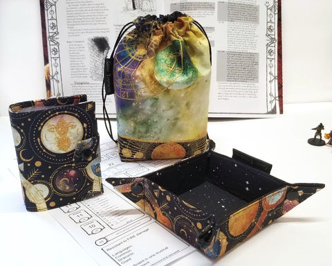 Cosmic Dice Bag bundle: Cosmos and space themed prints in warm tones on black starfield. Large Dice Bag, small dice tray, and spellbook. 