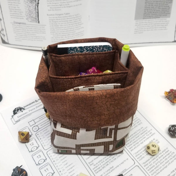 brown and cream dungeon map print dice bag. Top folded down to expose brown lining and pockets. 