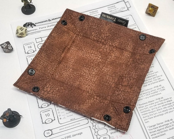 Dungeon map print dice tray, lined with brown crackle fabric, unsnapped and flat. 