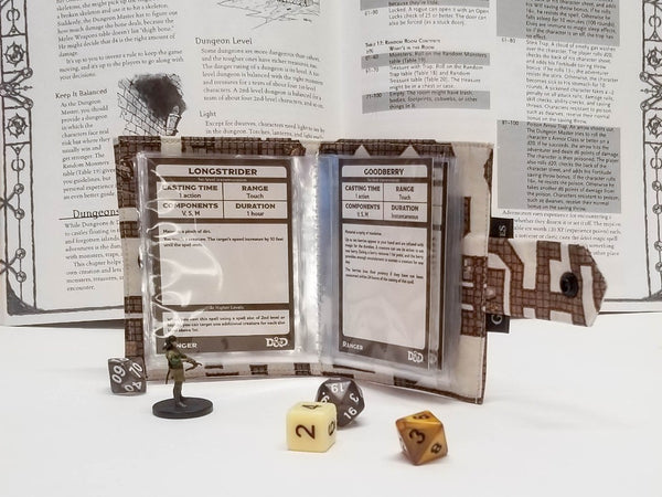 Spellbook made from fabric with a dungeon map on a light background. Open to show card sleeves