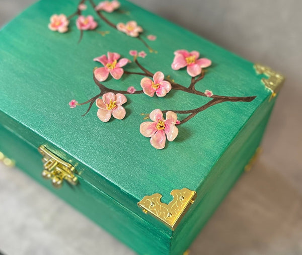 Cherry blossom chest in a shimmery mint green with 3D cherry blossoms and brass hardware.  Close up view of Blossoms