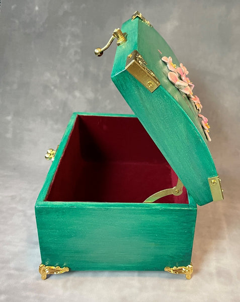 Cherry blossom chest in a shimmery mint green with 3D cherry blossoms and brass hardware.  Open showing cherry red lining. 